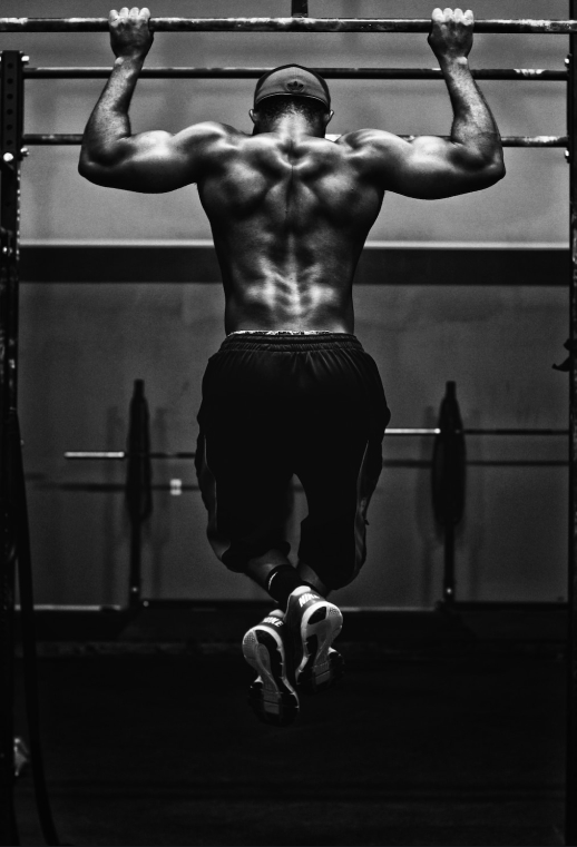 A man pulling himself up on a horizontal bar